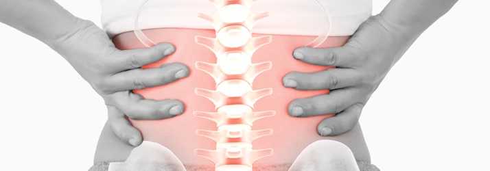 Close-up of a lower back with hands on both sides and an illustrated spine highlighted in red.
